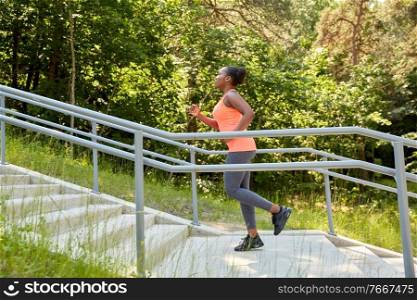 fitness, sport and healthy lifestyle concept - young african american woman running upstairs at park. young african american woman running upstairs