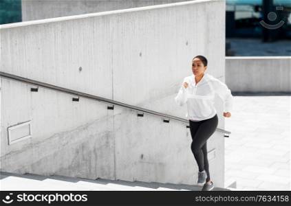 fitness, sport and healthy lifestyle concept - young african american woman running upstairs outdoors. african american woman running upstairs outdoors