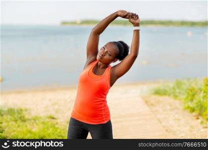 fitness, sport and healthy lifestyle concept - young african american woman stretching outdoors. young african american woman stretching outdoors
