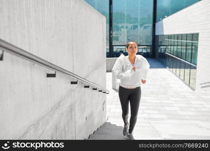fitness, sport and healthy lifestyle concept - young african american woman with earphones running upstairs outdoors. african american woman running upstairs outdoors