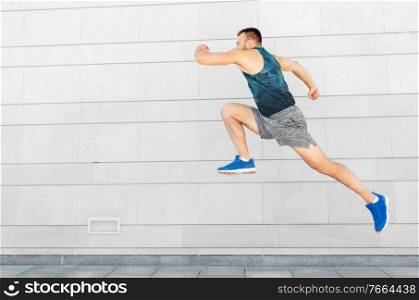 fitness, sport and healthy lifestyle concept - young man running or jumping outdoors. young man running or jumping outdoors