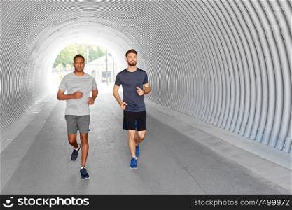 fitness, sport and healthy lifestyle concept - young men or male friends running outdoors. young men or male friends running outdoors