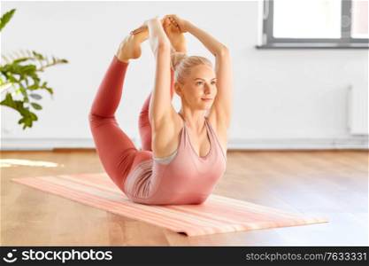 fitness, sport and healthy lifestyle concept - young woman doing bow pose at home or yoga studio. woman doing bow pose at home or yoga studio