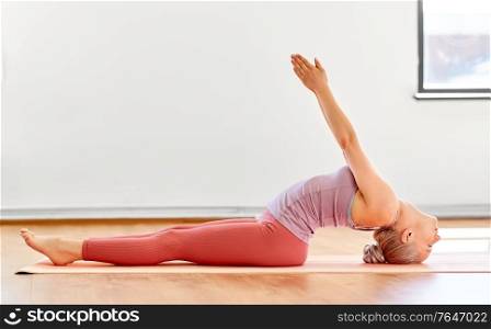fitness, sport and healthy lifestyle concept - young woman doing variation of fish pose on elbows at yoga studio. young woman doing fish pose at yoga studio