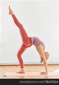 fitness, sport and healthy lifestyle concept - young woman doing variation of one-legged bridge pose at yoga studio. young woman doing bridge pose at yoga studio