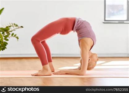 fitness, sport and healthy lifestyle concept - young woman doing variation of bridge pose on elbows at yoga studio. young woman doing bridge pose at yoga studio
