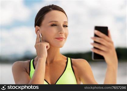 fitness, sport and healthy lifestyle concept - young woman with earphones and smartphone exercising outdoors. woman with earphones and smartphone doing sports