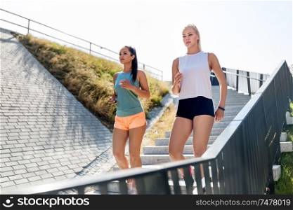 fitness, sport and healthy lifestyle concept - young women or female friends running or walking downstairs. young women or female friends running downstairs