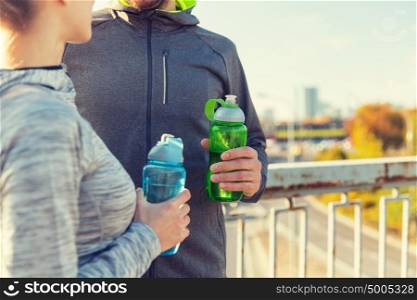 fitness, sport and lifestyle concept - close up of couple with bottles of water outdoors. close up of couple with water bottles outdoors