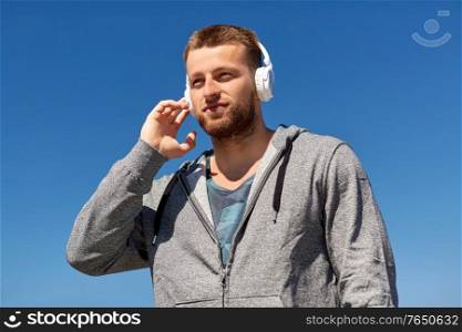 fitness, sport and lifestyle concept - young man in headphones listening to music outdoors. man in headphones listening to music outdoors