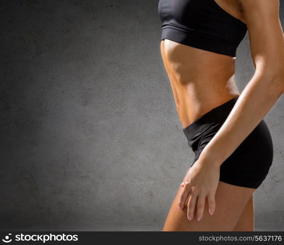 fitness, sport and people concept - close up of beautiful athletic female abs in sportswear over concrete wall background