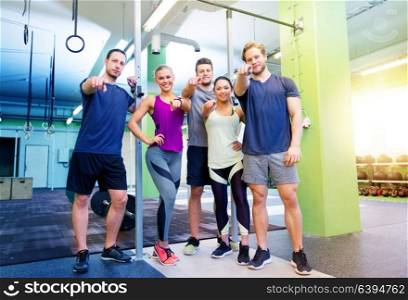 fitness, sport and people concept - group of happy friends pointing fingers at you in gym. happy friends pointing fingers at you in gym
