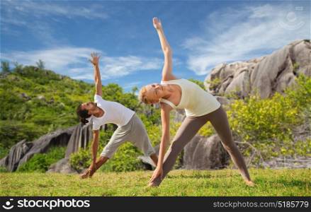 fitness, sport and people concept - happy couple doing yoga outdoors over natural background. happy couple doing yoga outdoors