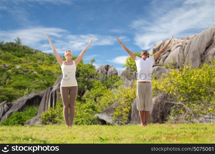 fitness, sport and people concept - happy couple making yoga and meditating over natural background. happy couple making yoga exercises on beach
