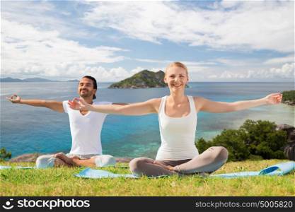 fitness, sport and people concept - happy couple making yoga exercises outdoors. happy couple making yoga exercises outdoors