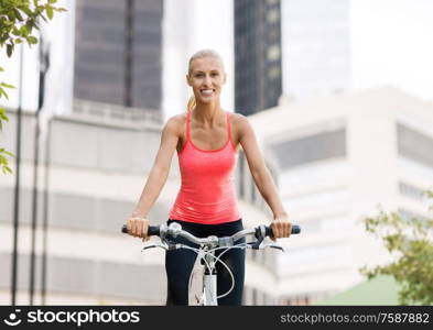 fitness, sport and people concept - happy young woman riding bicycle over city street on background. happy young woman riding bicycle at city