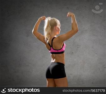 fitness, sport and people concept - smiling athletic woman in sportswear form back over concrete wall background