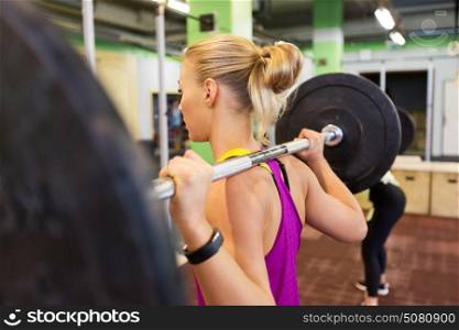 fitness, sport and people concept - woman with barbell at group training in gym. woman with barbell at group training in gym