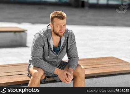 fitness, sport and people concept - young man sitting on bench outdoors. young man sitting on bench outdoors
