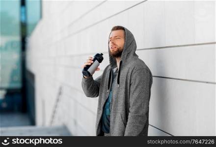 fitness, sport and people concept - young man with bottle of water in city. sportsman with bottle of water in city