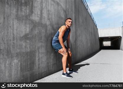 fitness, sport and people concept - young tired man outdoors. tired young man doing sports outdoors