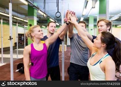 fitness, sport and teamwork concept - group of happy people or friends making high five in gym. group of happy friends making high five in gym