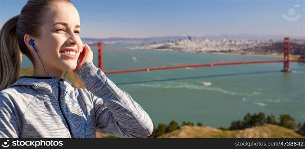 fitness, sport and technology concept - close up of happy woman listening to music in earphones over golden gate bridge in san francisco bay background. close up of woman listening to music in earphones. close up of woman listening to music in earphones