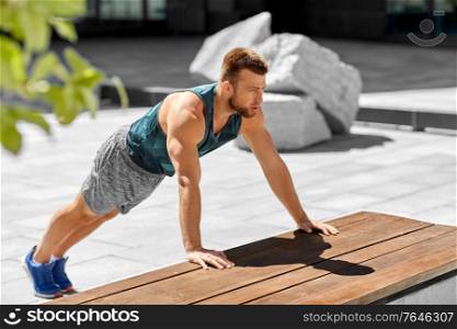 fitness, sport and training concept - young man doing push ups on city street. young man doing push ups on city street