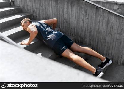 fitness, sport and training concept - young man doing push ups on stairs outdoors. young man doing push ups on stairs outdoors