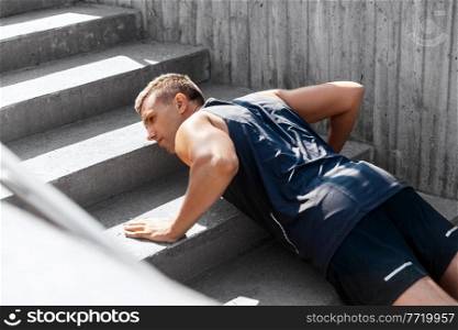 fitness, sport and training concept - young man doing push ups on stairs outdoors. young man doing push ups on stairs outdoors