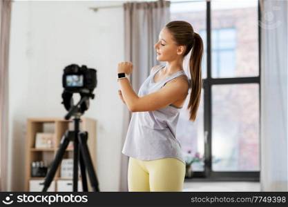 fitness, sport and video blogging concept - happy smiling teenage girl or blogger with camera on tripod recording online gym class at home. teenage girl or blogger recording gym class video