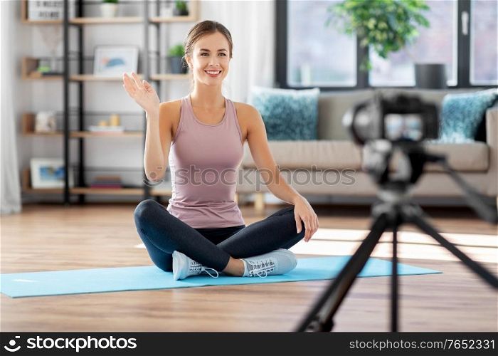 fitness, sport and video blogging concept - happy smiling woman or blogger with camera streaming online yoga class at home. woman or sports blogger streaming online at home