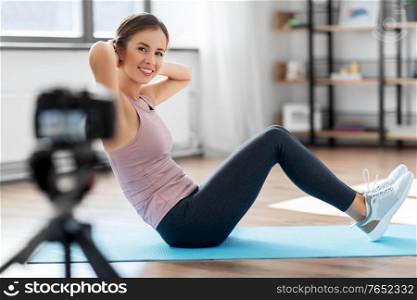 fitness, sport and video blogging concept - happy smiling woman or blogger with camera streaming online tutorial at home. woman or sports blogger streaming online at home
