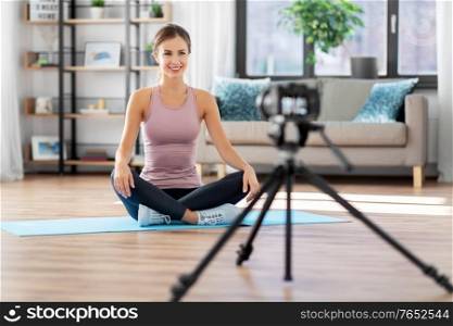 fitness, sport and video blogging concept - woman or blogger with camera streaming online yoga class at home. woman or sports blogger streaming online at home