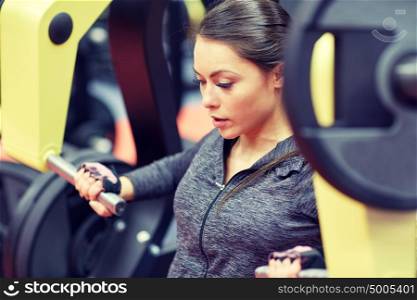 fitness, sport, bodybuilding, exercising and people concept - close up of young woman flexing muscles on seated chest press machine in gym. woman flexing muscles on chest press gym machine