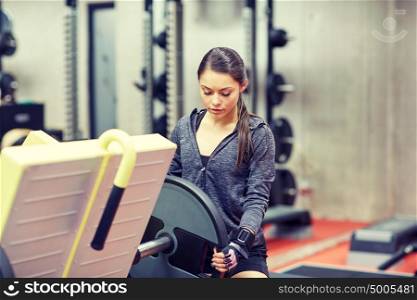 fitness, sport, bodybuilding, exercising and people concept - young woman adjusting leg press machine in gym. young woman adjusting leg press machine in gym