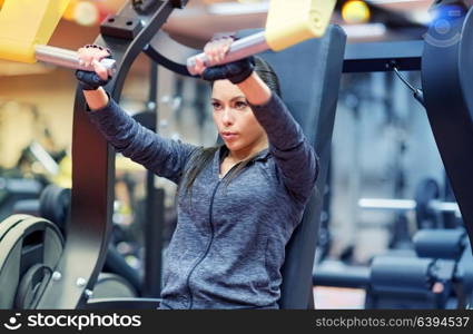 fitness, sport, bodybuilding, exercising and people concept - young woman flexing muscles on seated chest press machine in gym. woman flexing muscles on chest press gym machine
