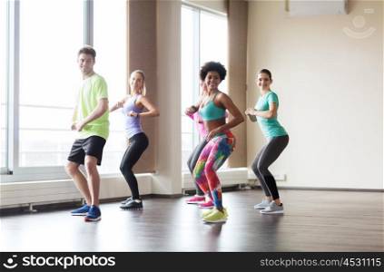 fitness, sport, dance and healthy lifestyle concept - group of smiling people with coach dancing in gym or studio. group of smiling people dancing in gym or studio