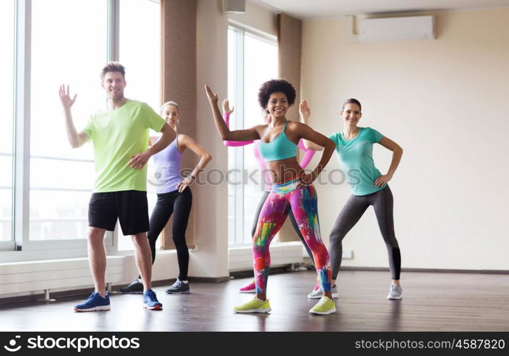 fitness, sport, dance and healthy lifestyle concept - group of smiling people with coach dancing in gym or studio