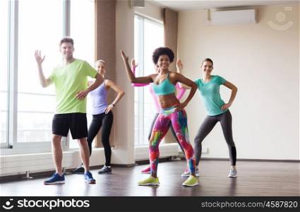 fitness, sport, dance and healthy lifestyle concept - group of smiling people with coach dancing in gym or studio