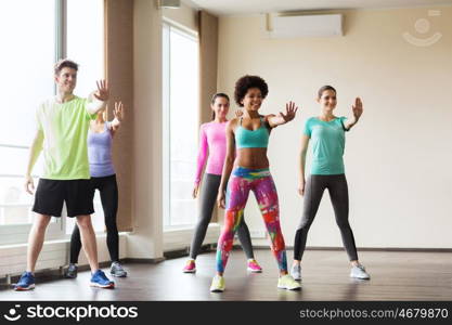 fitness, sport, dance and healthy lifestyle concept - group of smiling people with coach dancing in gym or studio