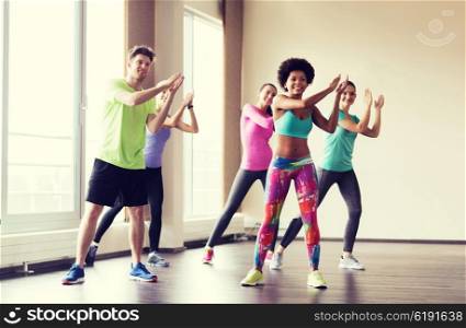 fitness, sport, dance and lifestyle concept - group of smiling people with coach dancing in gym or studio