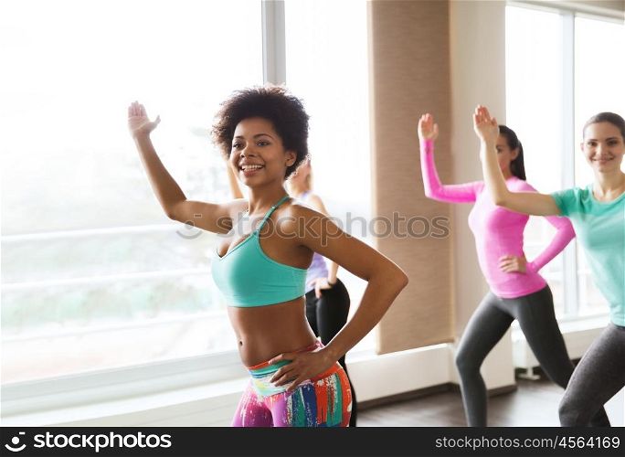 fitness, sport, dance and lifestyle concept - group of smiling young woman with coach dancing in gym or studio