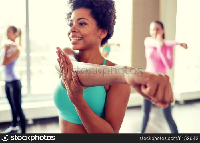 fitness, sport, dance, people and lifestyle concept - close up of smiling african american woman with group of women dancing zumba in gym or studio