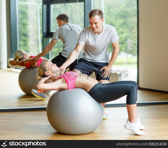 fitness, sport, exercising and diet concept - smiling young woman and personal trainer in gym