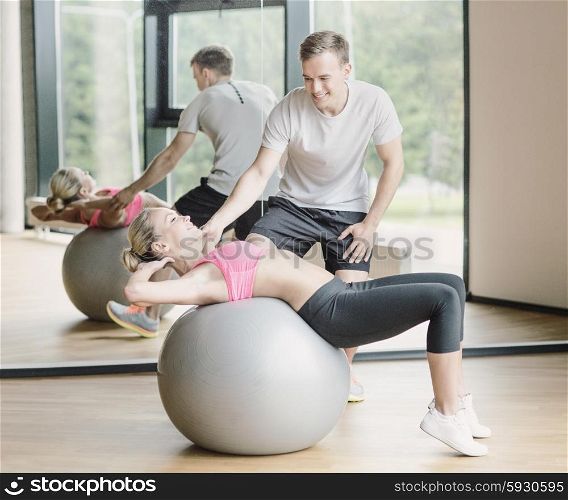 fitness, sport, exercising and diet concept - smiling young woman and personal trainer in gym