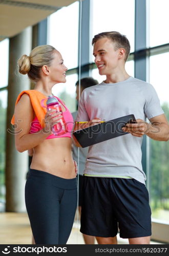 fitness, sport, exercising and diet concept - smiling young woman with personal trainer after training in gym