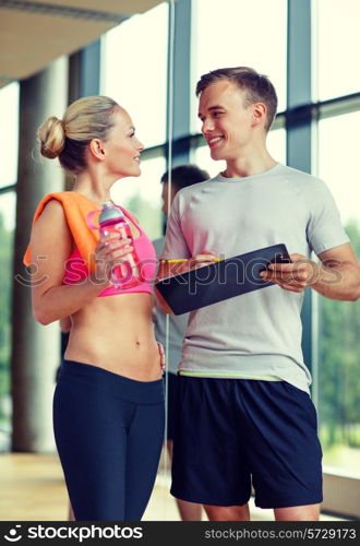 fitness, sport, exercising and diet concept - smiling young woman with personal trainer after training in gym