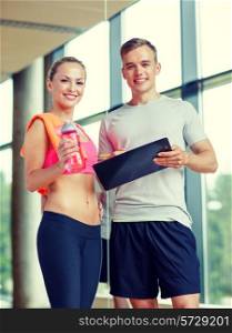fitness, sport, exercising and diet concept - smiling young woman with personal trainer after training in gym