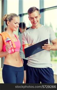 fitness, sport, exercising and diet concept - smiling young woman with personal trainer after training in gym